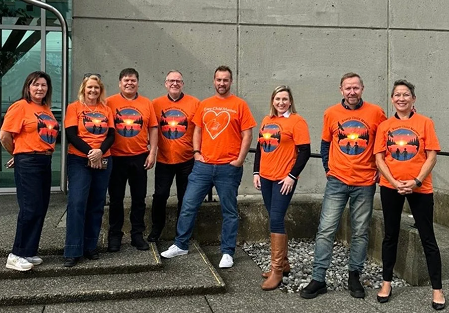 The IGV team standing together outside in matching orange t-shirts